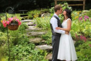 A young couple share a romantic kiss in the garden after choosing to elope in Vermont, trusting all the details to us and our Vermont Elopement Package.