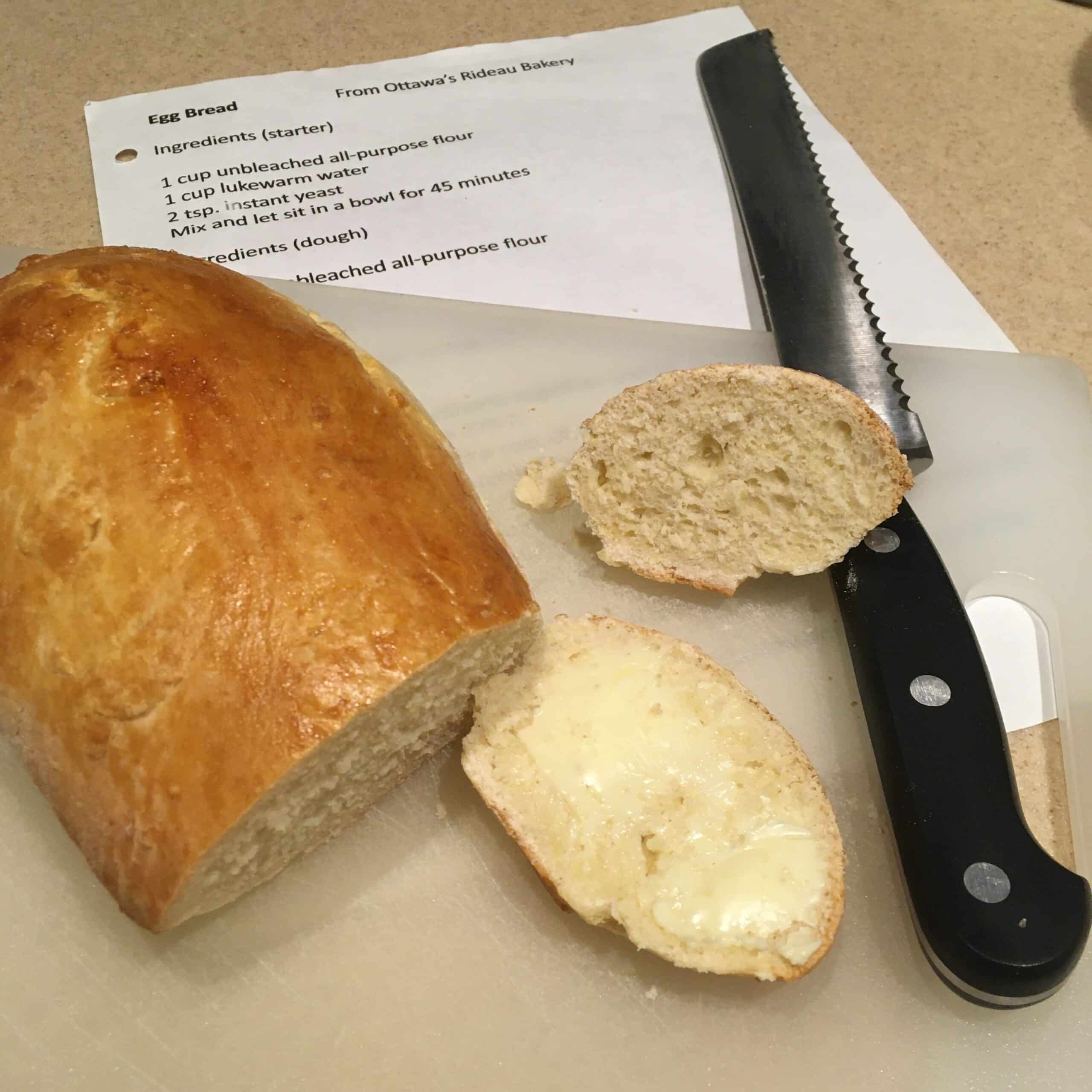 Bread loaf with buttered slice and bread knife.